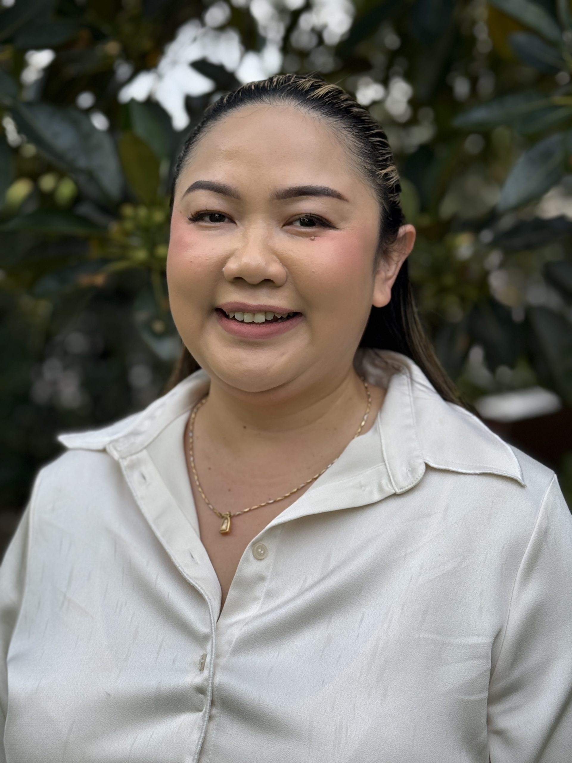 Smiling woman outdoors wearing white blouse.