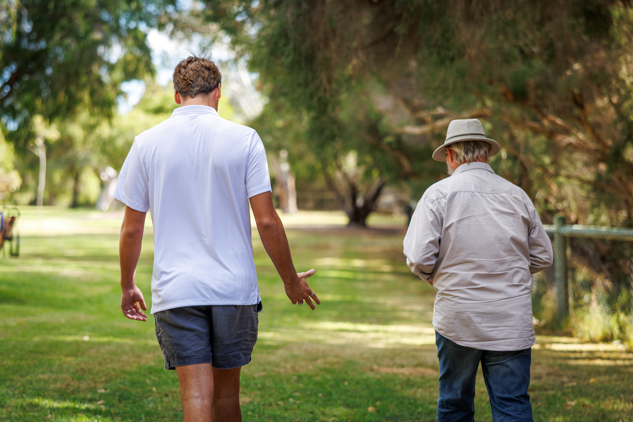 Two people walking in a park, seen from behind.
