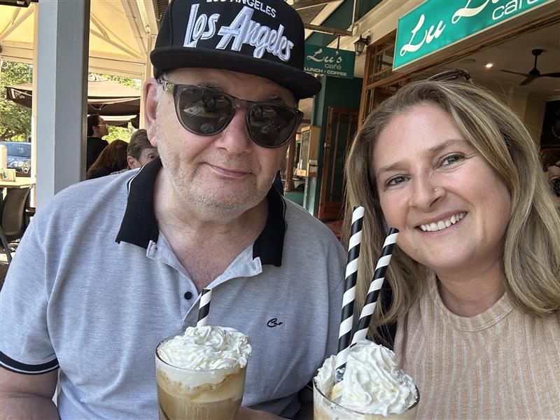 Smiling pair enjoying iced coffee outdoors